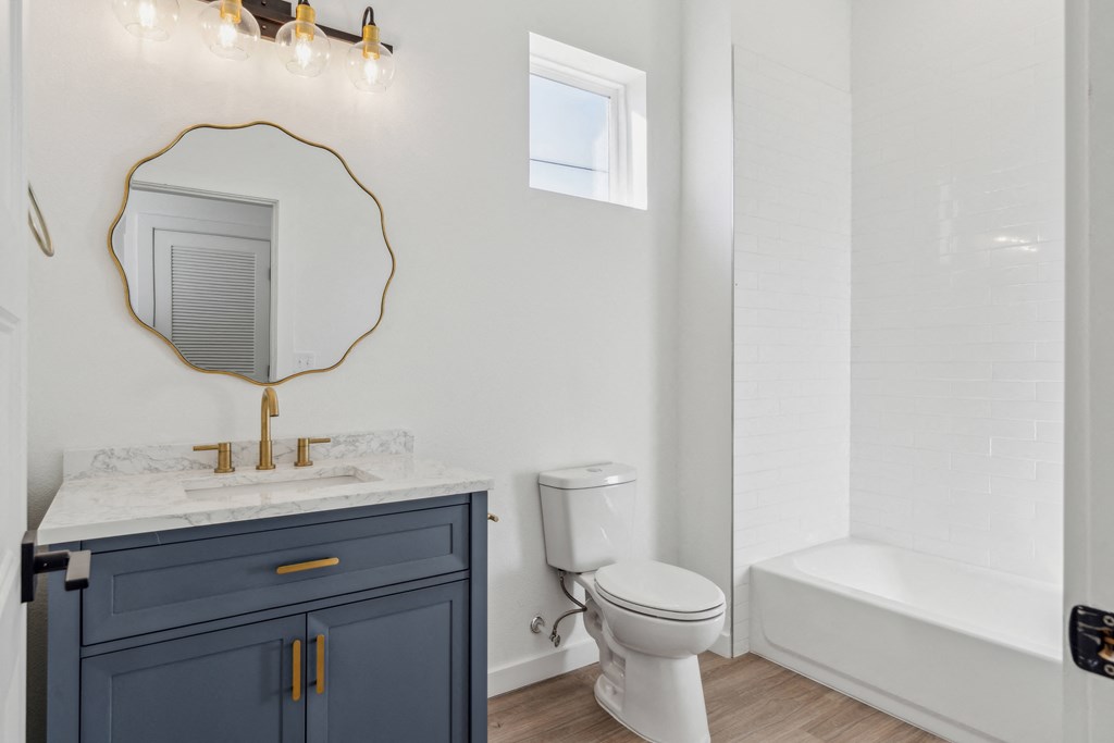 A bathroom with a toilet, sink, and a mirror.