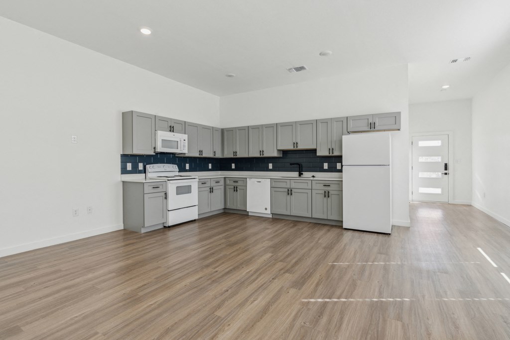 A kitchen with white cabinets and a wooden floor.