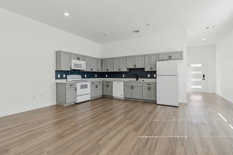 A kitchen with white cabinets and a wooden floor.