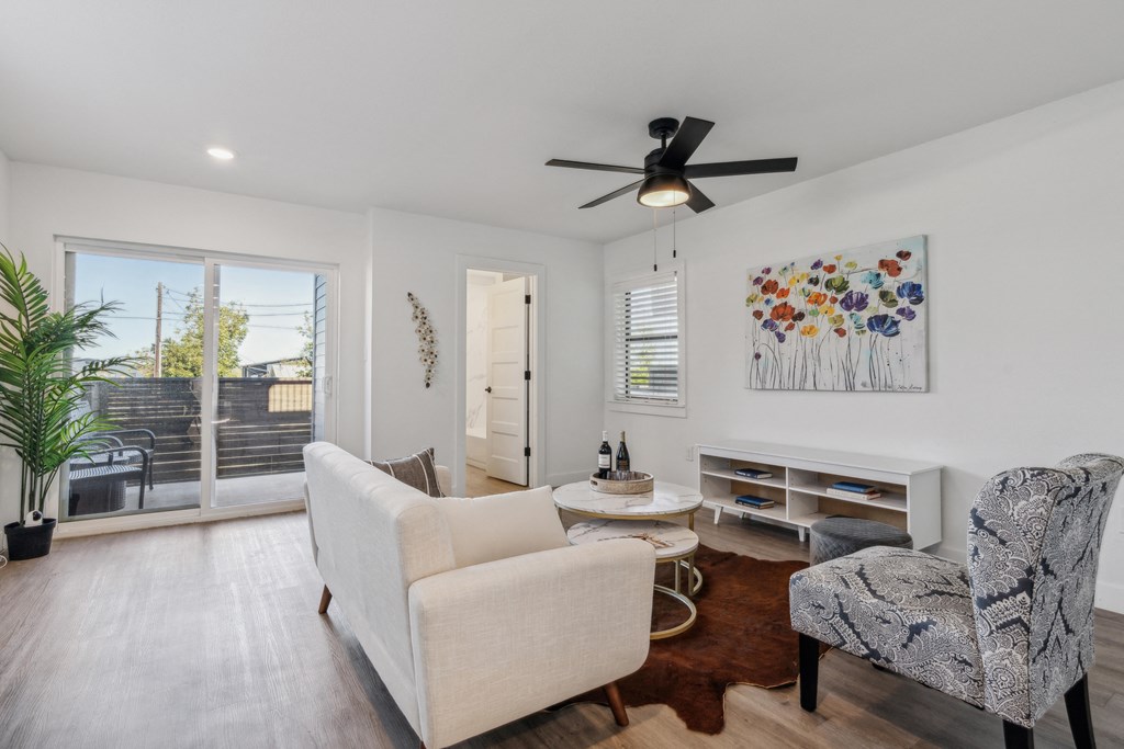 A living room with a white couch, a chair, and a painting on the wall.
