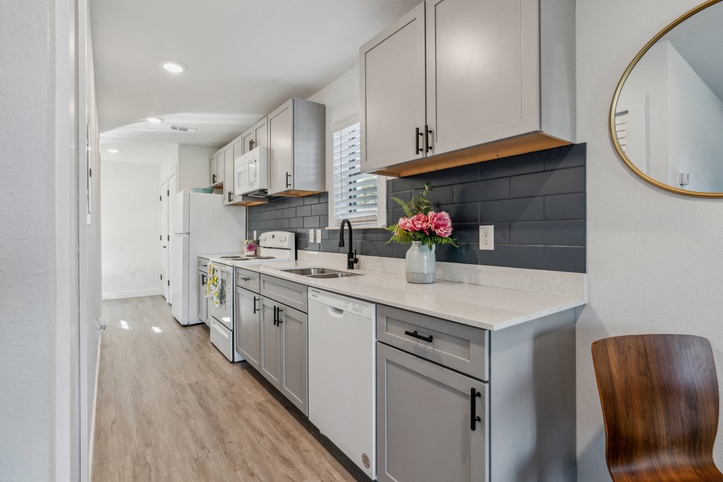 A kitchen with white cabinets and a wooden chair.