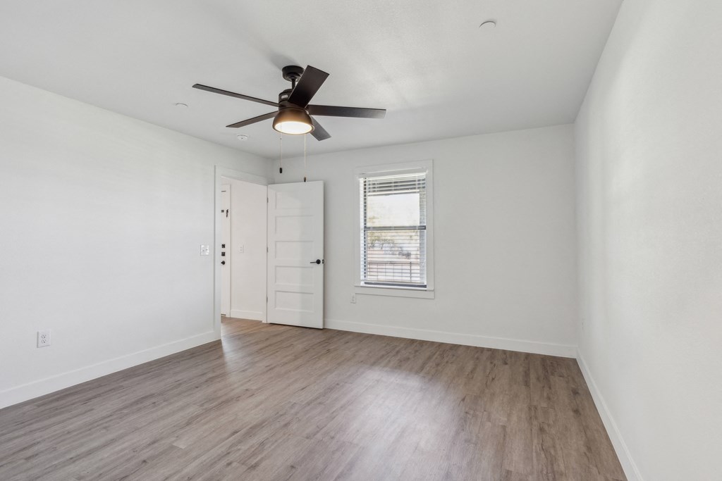 A room with a ceiling fan and a window with blinds.
