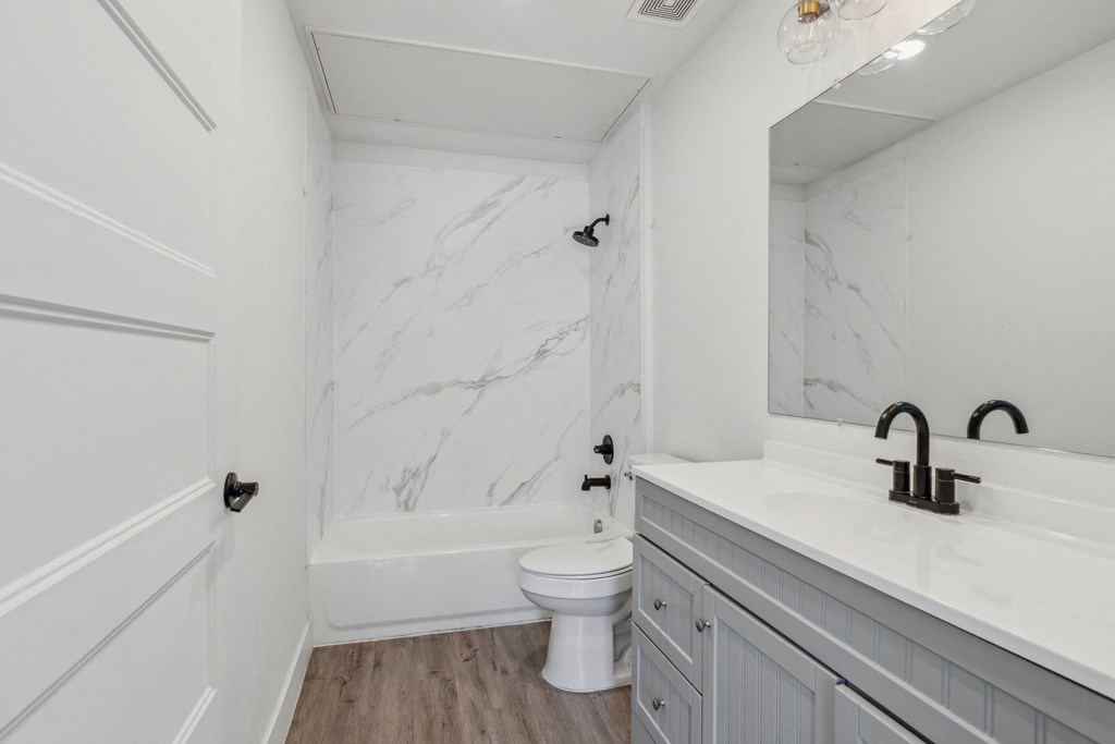 A white bathroom with a marble wall and a toilet.