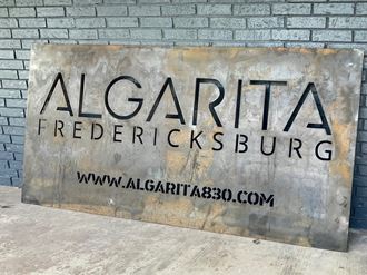 a large metal sign in front of a brick wall