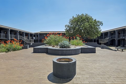 a courtyard with a fountain and plants in front of a building