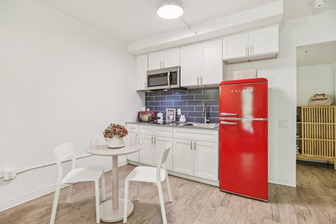 a small kitchen with a red refrigerator and a table and chairs