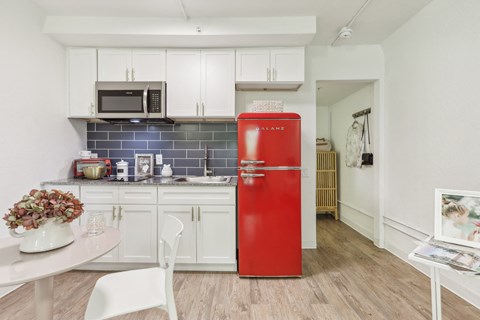 a kitchen with white cabinets and a red refrigerator