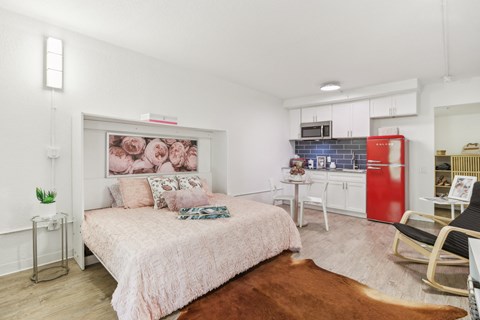 a bedroom with a bed and a kitchen with a red refrigerator