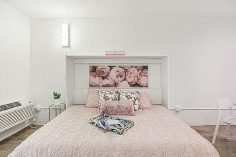 a bedroom with a bed and a painting of roses on the wall