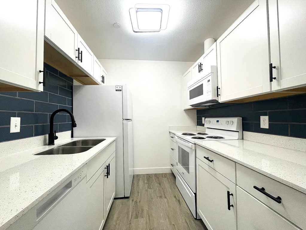 an empty kitchen with white cabinets and appliances and a sink