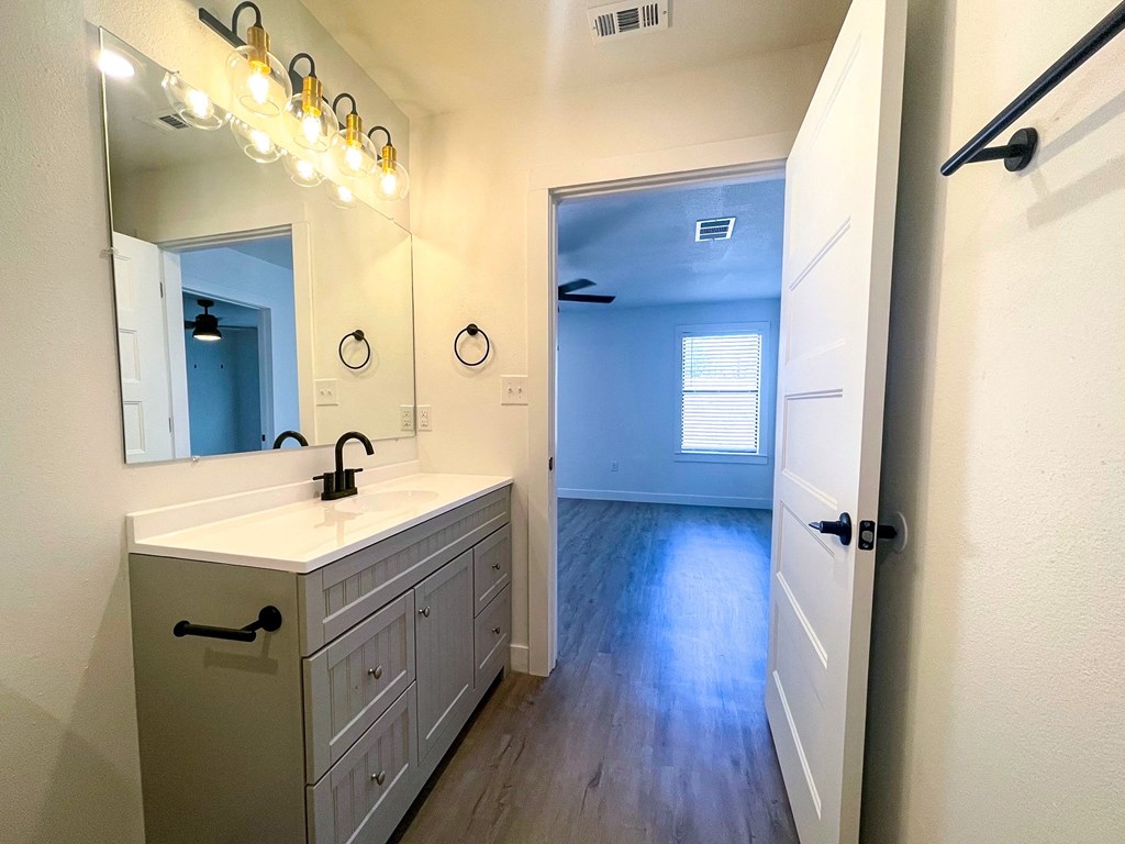 a bathroom with a sink and a mirror and a hallway
