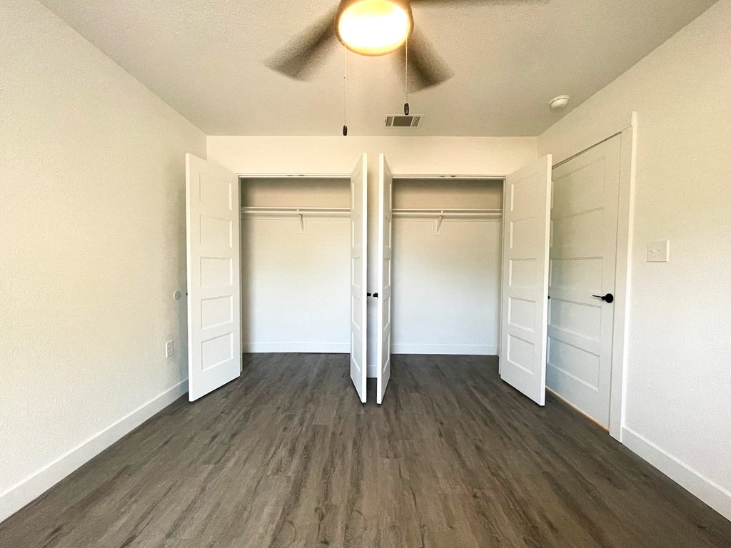 an empty living room with two closets and a ceiling fan
