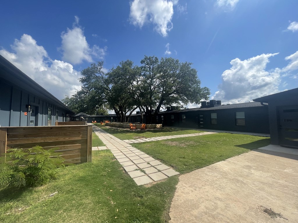 a view of the outside of a building with a sidewalk and grass