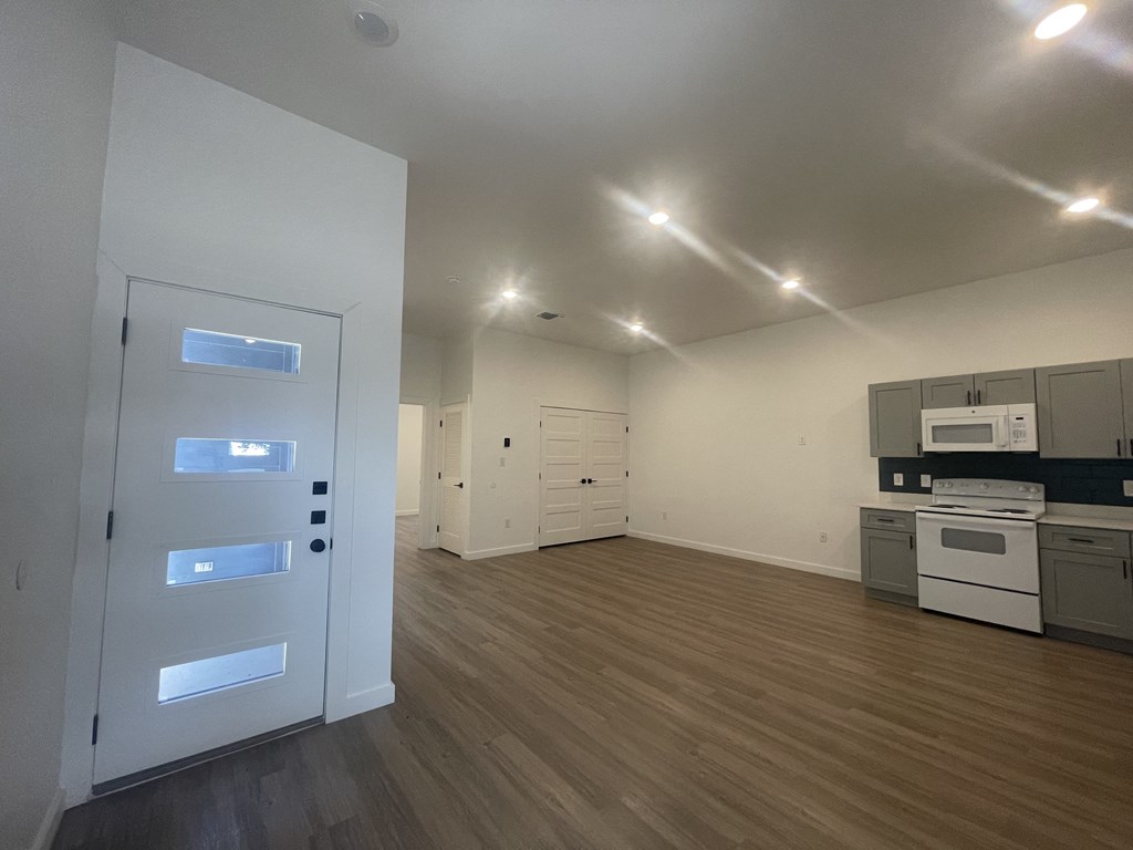 an empty living room with a door to a kitchen