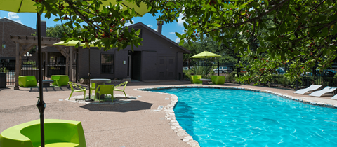 A pool surrounded by green chairs and umbrellas.