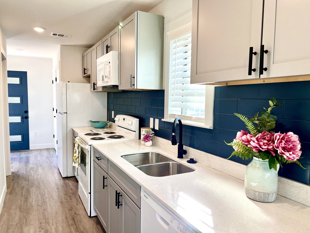 a kitchen with white cabinets and a sink and a window