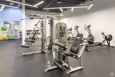 a gym with cardio machines and weights at the district at highland village apartments