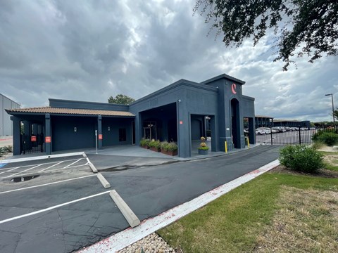 a blue building with a parking lot and a cloudy sky