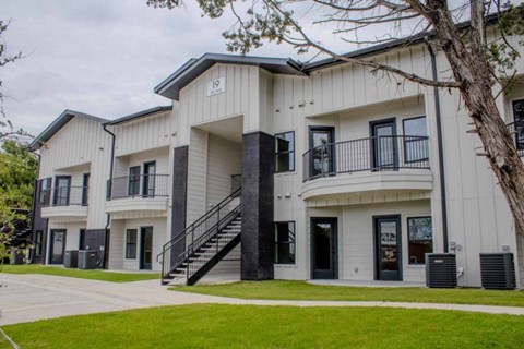 A modern two-story apartment building with a balcony on the second floor.