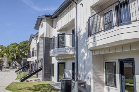 A modern two-story apartment building with a balcony on the second floor.
