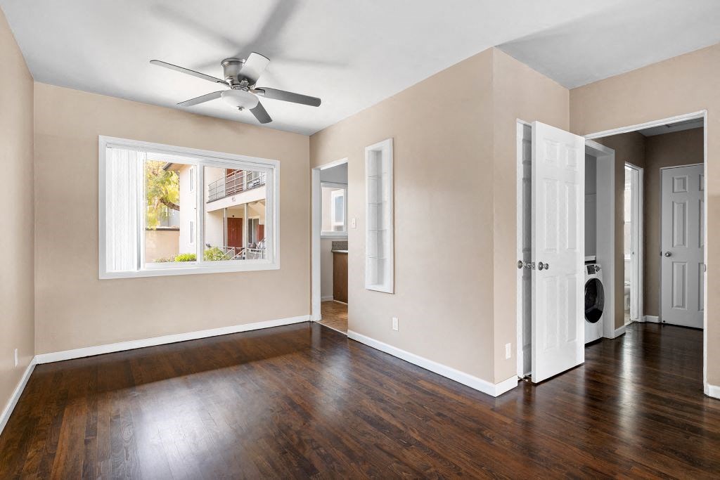 an empty room with a large window and a ceiling fan