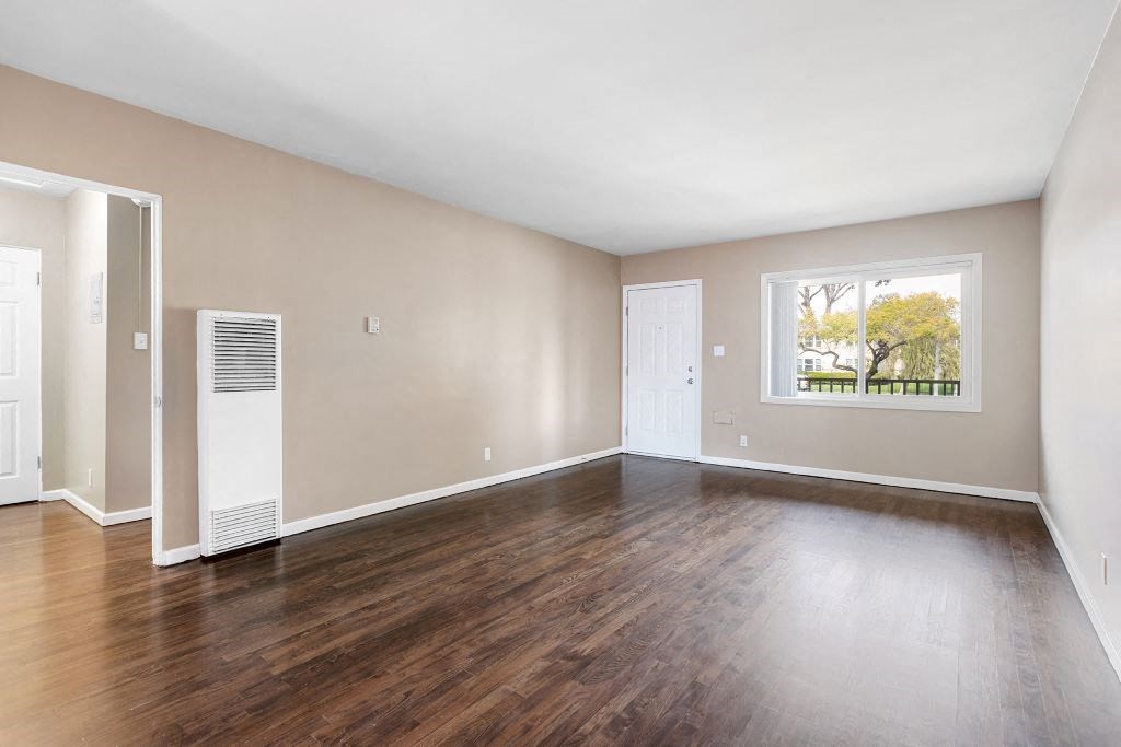 a bedroom with hardwood floors and a large window