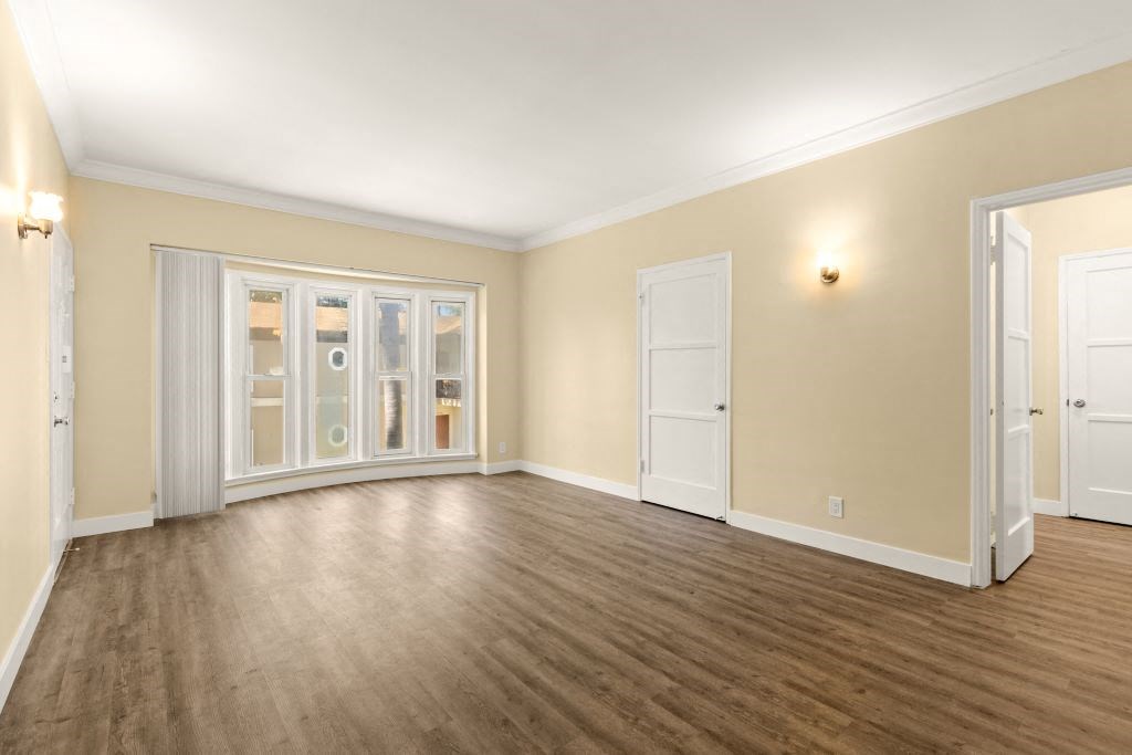 the living room of an empty home with wood floors and doors
