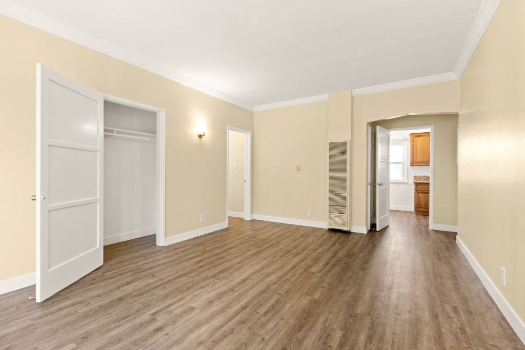 a living room with a hard wood floor and a door to a closet