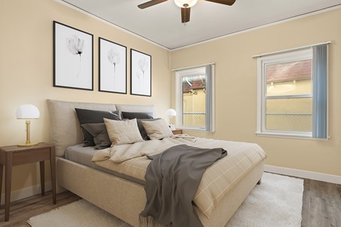 A bedroom with a bed, a ceiling fan, and three framed pictures on the wall.