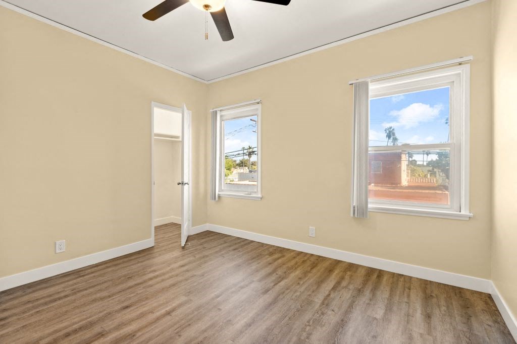 an empty living room with wood floors and a ceiling fan