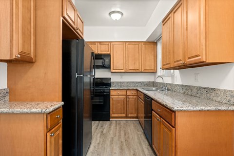 A kitchen with wooden cabinets and a black refrigerator.