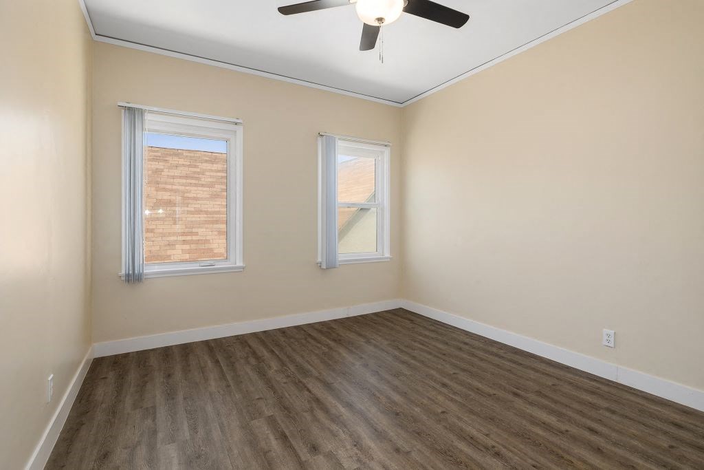 an empty room with two windows and a ceiling fan