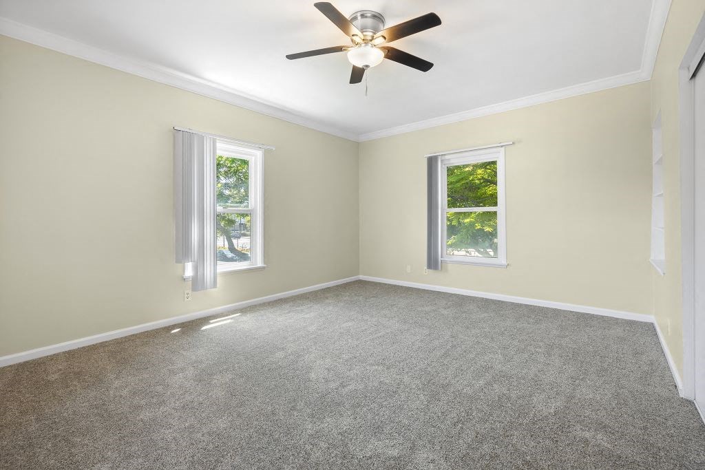a bedroom with two windows and a ceiling fan