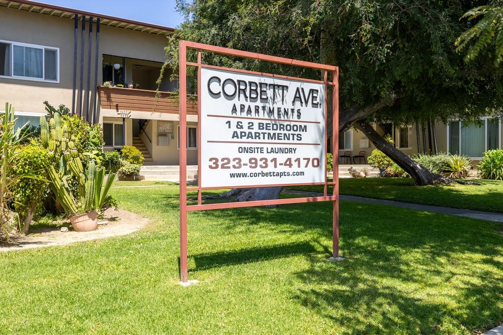 A sign for Corbett Ave Apartments stands in front of a building.