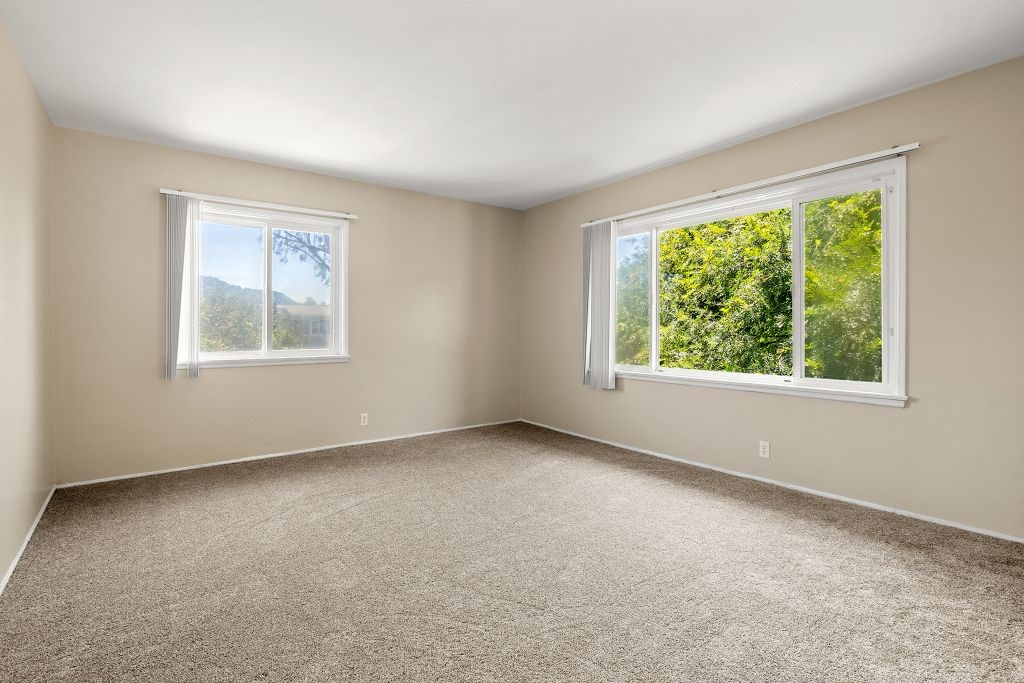 A room with two windows and carpeted floor.