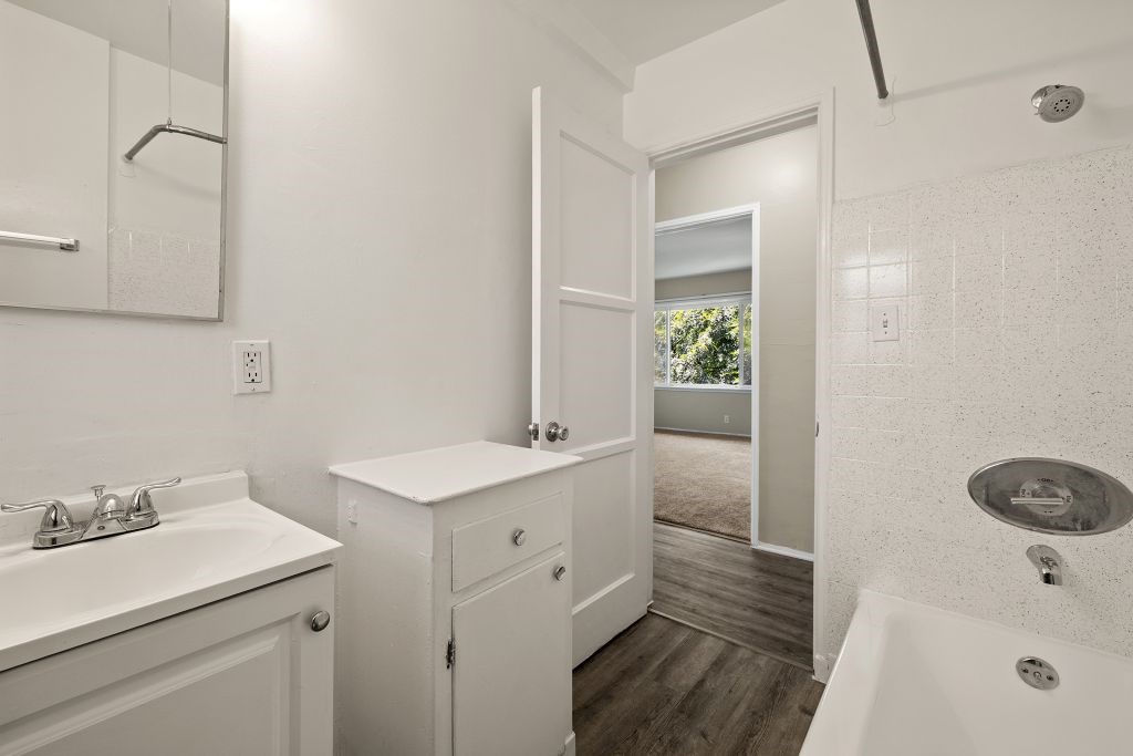 A white bathroom with a white sink and a white tub.