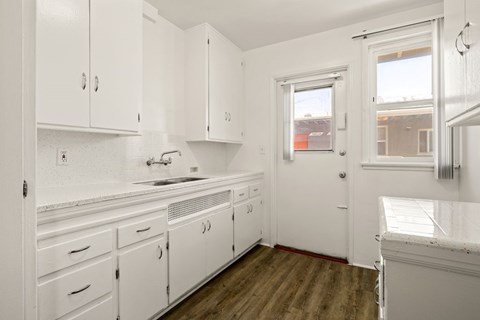 A kitchen with white cabinets and a window.