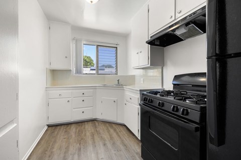 A black stove in a white kitchen with a window.