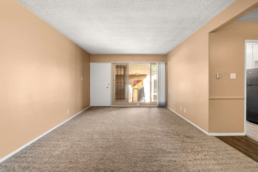 a living room with a carpeted floor and a door to a hallway