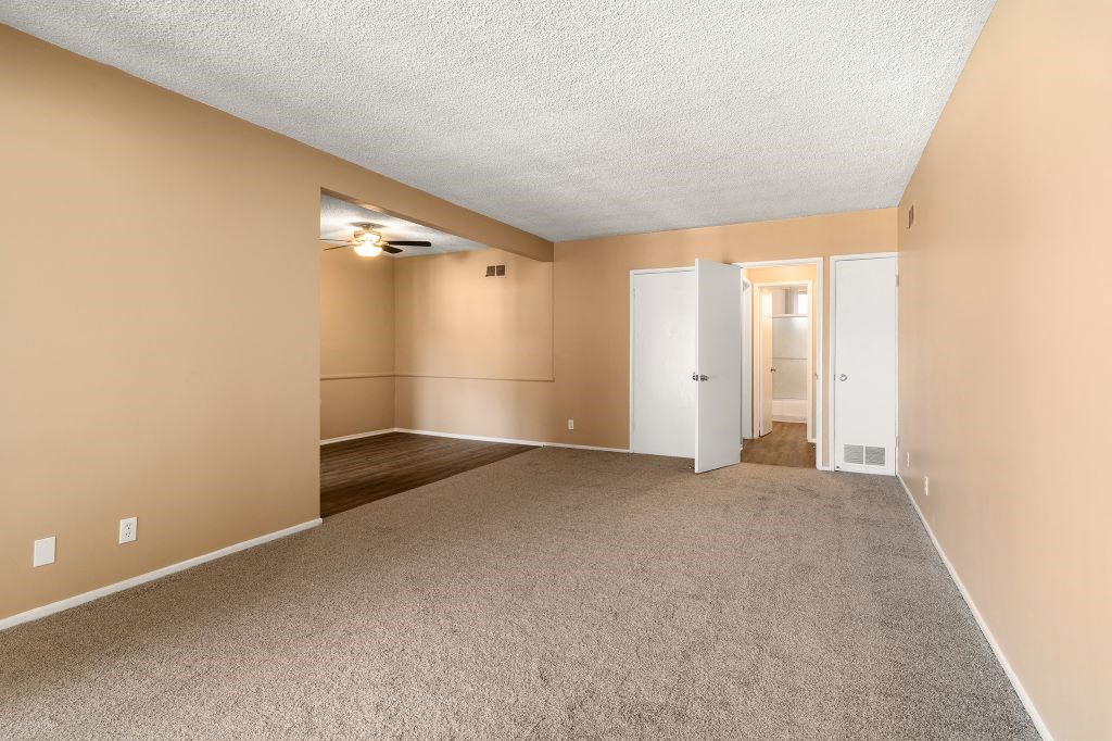 an empty living room with carpet and a door to a hallway