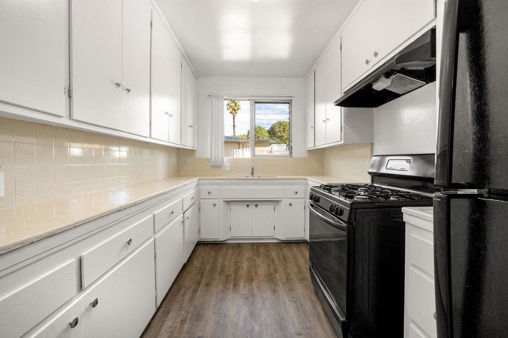 a kitchen with white cabinets and black appliances