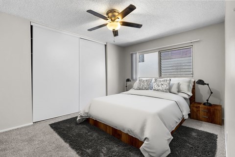 A bedroom with a bed, a ceiling fan, and a window.