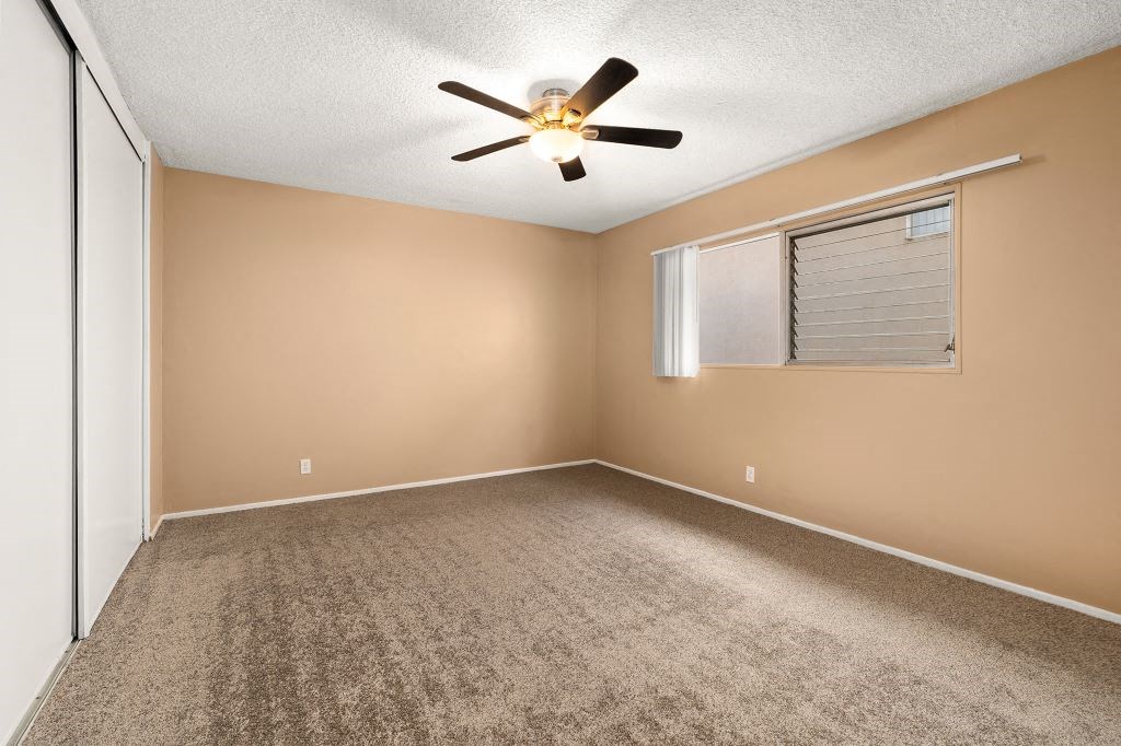 an empty bedroom with a ceiling fan and a window