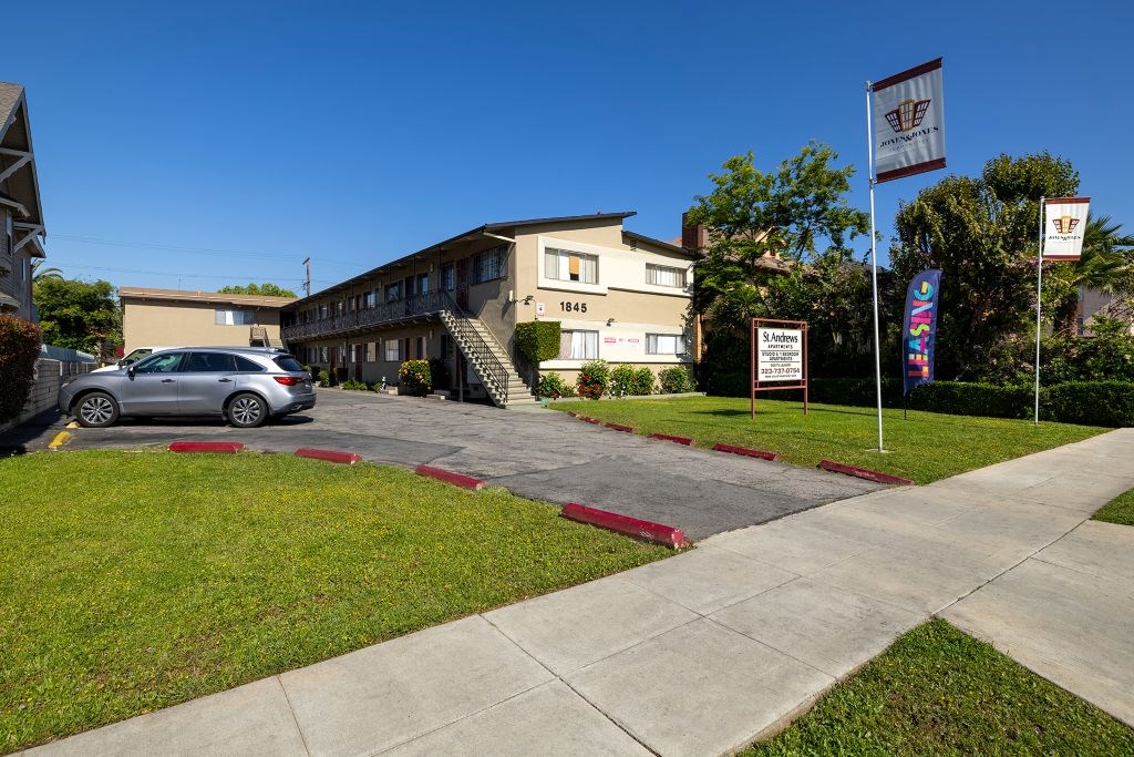 A building with a flag on the right side and a car parked in front.