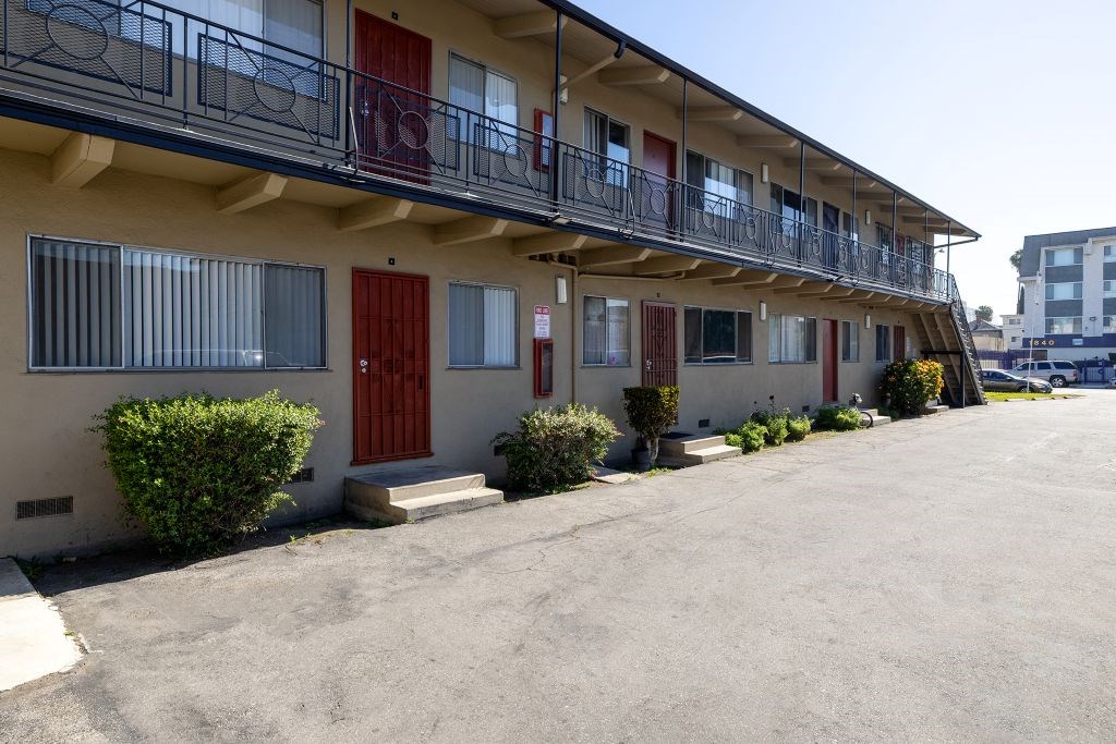 A row of apartment buildings with balconies and red doors.