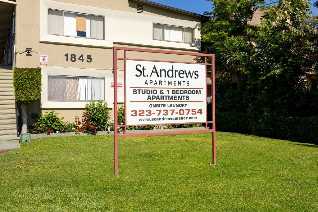 A sign for St. Andrews Apartments is displayed in front of a building.
