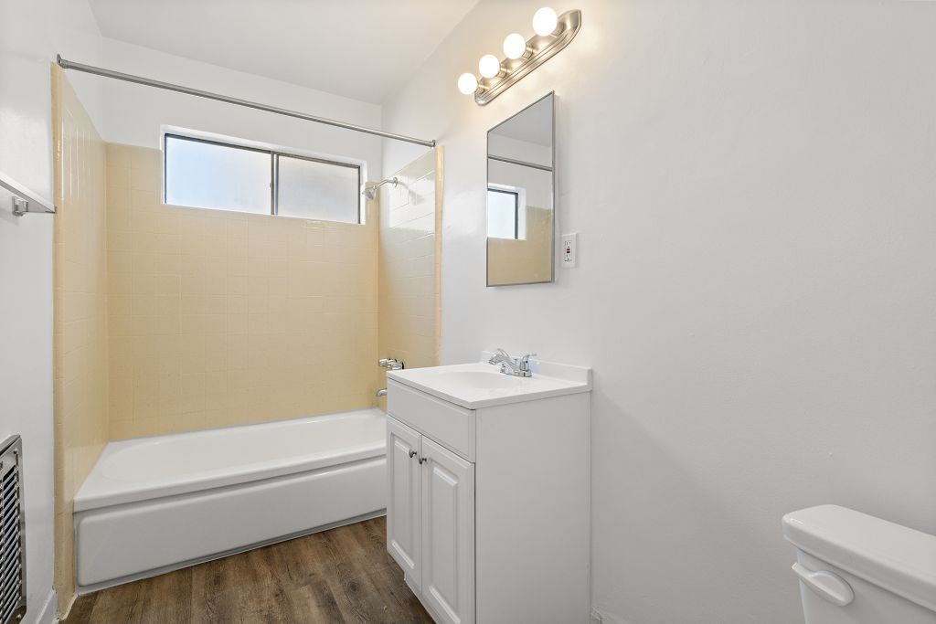 A white bathroom with a white tub, sink, and vanity.