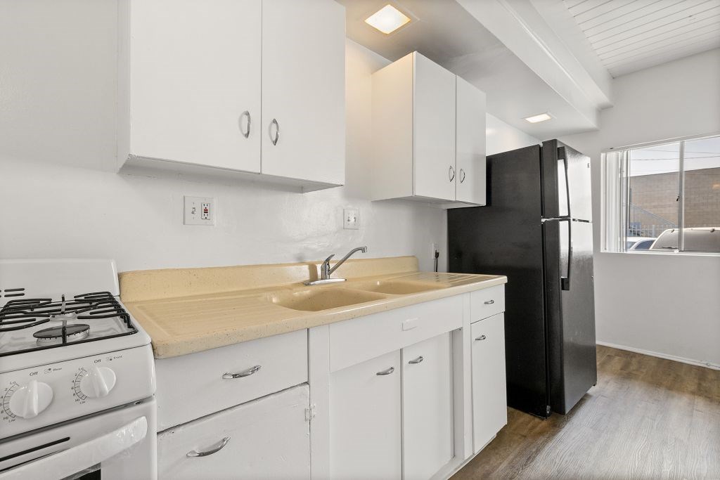 A modern kitchen with white cabinets and a black refrigerator.