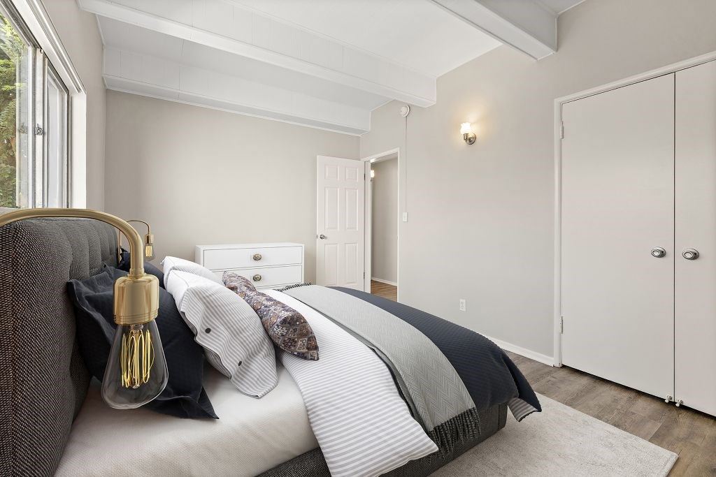 A bedroom with a bed, a chair, and a wardrobe.