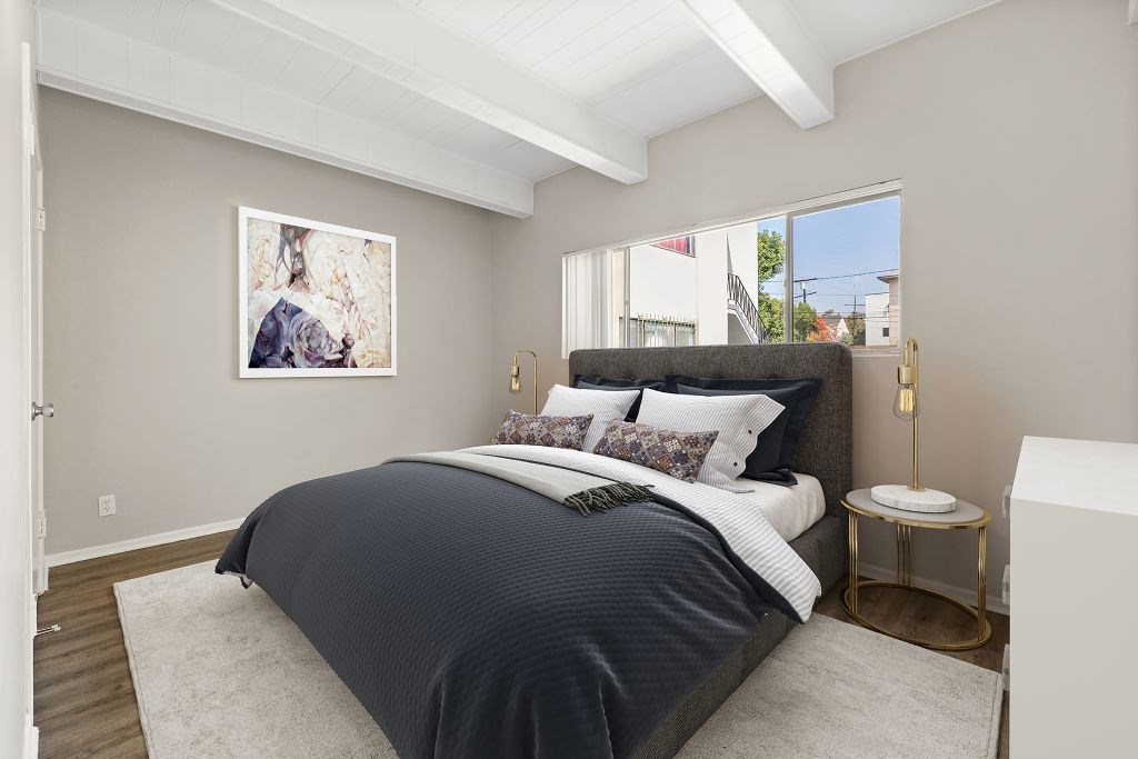 A bedroom with a large bed and a painting on the wall.